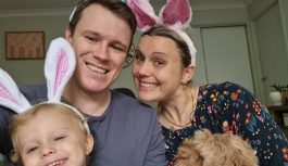 Young family smiling while wearing bunny ears.